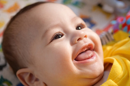 Happy newborn baby makes a funny face. Portrait of a crawling baby in his room close up.の写真素材