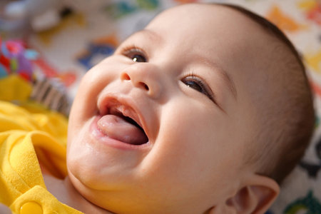 Happy newborn baby makes a funny face. Portrait of a crawling baby in his room close up.の写真素材