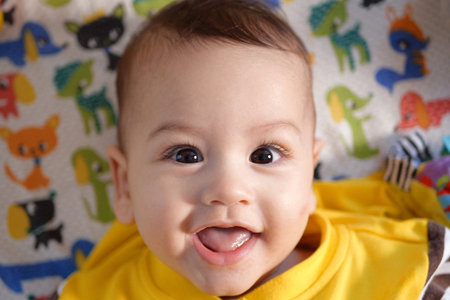 Happy newborn baby makes a funny face. Portrait of a crawling baby in his room close up.