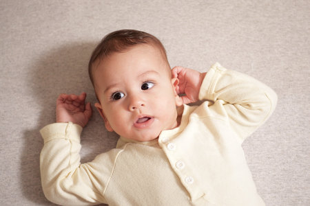 Happy newborn baby makes a funny face. Portrait of a crawling baby in his room close up.の写真素材