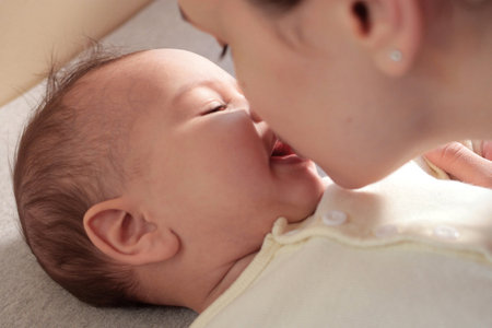Young mother kissing her baby boy at home. family concept. Closeup portrait of loving mother young woman kissing little kid, home interior.の写真素材