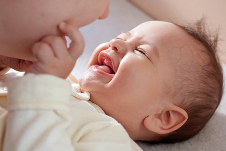 Young mother kissing her baby boy at home. family concept. Closeup portrait of loving mother young woman kissing little kid, home interior.の写真素材