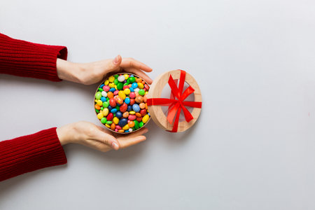 Female hands with delicious candies in box on color background.の写真素材