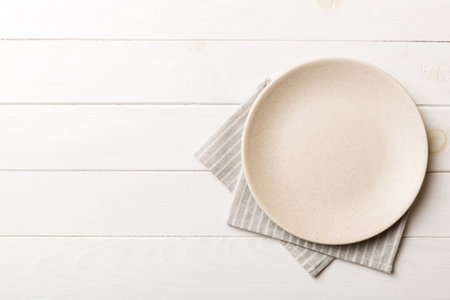 Top view on colored background empty round white plate on tablecloth for food. Empty dish on napkin with space for your design.の写真素材