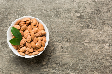 Fresh healthy Almond in bowl on colored table background. top view.の写真素材