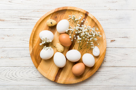 Happy Easter composition. Easter eggs in basket on colored table with gypsophila. Natural dyed colorful eggs background top view with copy space.の写真素材