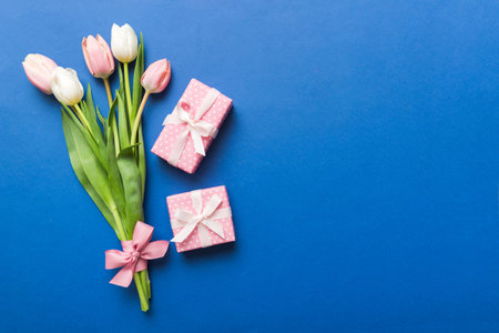 Pink tulips flowers and gift or present box on colored table background. Mothers Day, Birthday, Womens Day, celebration concept. Space for text view.の写真素材