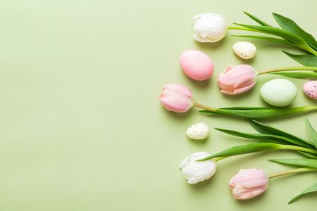 Happy Easter composition. Easter eggs on colored table with yellow Tulips. Natural dyed colorful eggs background top view with copy space.の写真素材
