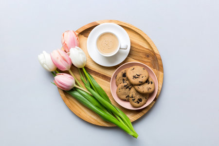 Cup of coffee mug with coffee, cookies and tulips on a colored background. Greeting spring card top view.の写真素材