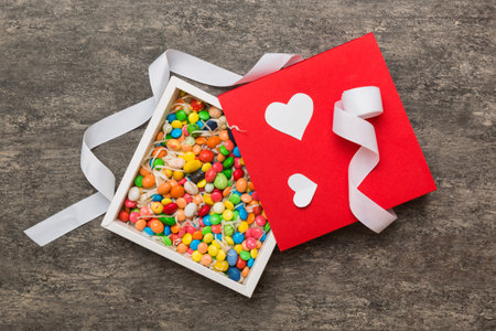 Valentine day composition: sweet candy, with gift boxes with bow and red felt hearts, photo...