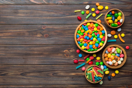 different colored round candy in bowl and jars. Top view of large variety of sweets and candies with copy space.の写真素材
