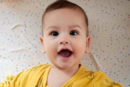 Happy newborn baby makes a funny face. Portrait of a crawling baby in his room close up.の写真素材