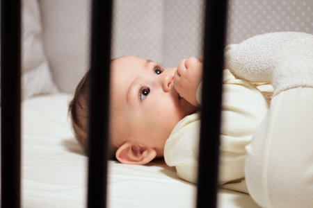 Baby sucking Pacifier looking on bed. portrait of cute newborn baby lying on bed with pacifier on...