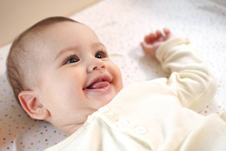 Happy newborn baby makes a funny face. Portrait of a crawling baby in his room close up.