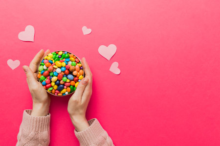 Female hands with delicious candies in box on color background.の写真素材