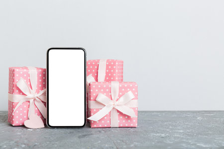 mobile phone with blank screen on colored background with hearts, calendar and gift box, valentine day concept perspertive view flat lay.の写真素材