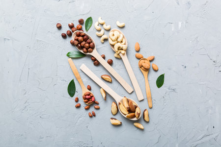 mixed nuts in white wooden spoon. Mix of various nuts on colored background. pistachios, cashews, walnuts, hazelnuts, peanuts and brazil nuts.の写真素材