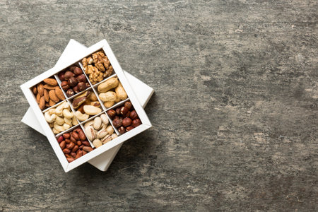 Various varieties of nuts lying in paper box on table background. top view. Health food. Close up, copy space, top view, flat lay. Walnut, pistachios, almonds, hazelnuts and cashews.の写真素材