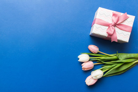Pink tulips flowers and gift or present box on colored table background. Mothers Day, Birthday, Womens Day, celebration concept. Space for text view.の写真素材