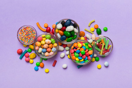 different colored round candy in bowl and jars. Top view of large variety of sweets and candies with copy space.の写真素材