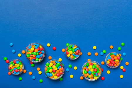 different colored round candy in bowl and jars. Top view of large variety of sweets and candies with copy space.の写真素材
