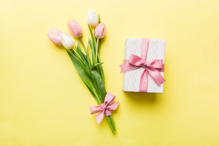 Pink tulips flowers and gift or present box on colored table background. Mothers Day, Birthday, Womens Day, celebration concept. Space for text view.の写真素材