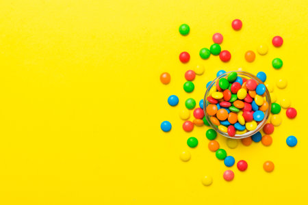 Multicolored candies in a bowl on a colored background. birthday and holiday concept. Top view with copy space.の写真素材