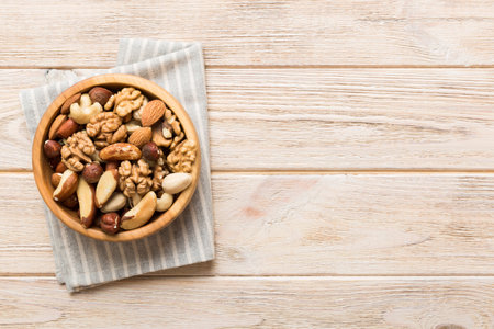 mixed nuts in bowl. Mix of various nuts on colored background. pistachios, cashews, walnuts,...