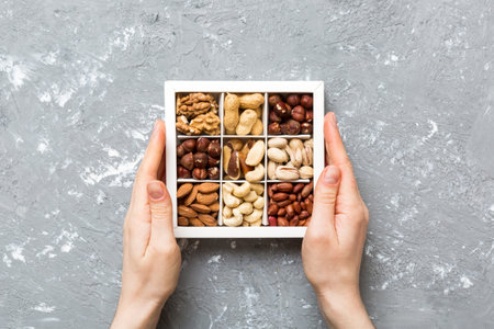 Young woman holding box with different nuts, closeup. Close up, copy space, top view, flat lay....