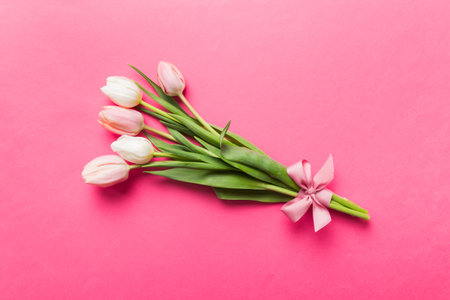 Bouquet of pink tulips on colored table background. Top view with copy space. waiting for spring. happy easter card. flat lay.の写真素材
