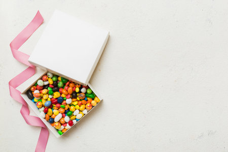 Set of different sweet candy in a paper box with a satin ribbon on a colored background. holiday concept.の写真素材