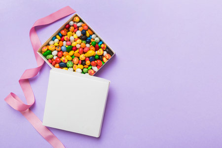 Set of different sweet candy in a paper box with a satin ribbon on a colored background. holiday concept.の写真素材