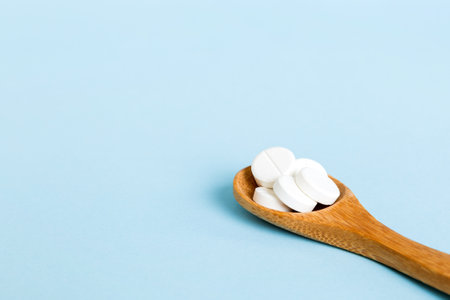 Heap of white pills on colored background. Tablets scattered on a table. Pile of red soft gelatin capsule. Vitamins and dietary supplements concept.の写真素材