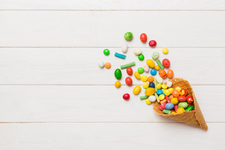 waffle cone full of assorted traditional candies falling out on colored background with copy space. Happy Holidays sale concept.の写真素材