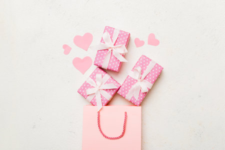 Gift boxes pop out from paper bag top view on colored background. bag packing handmade boxes fall out Concept of holidays, shopping, sale, discounts. Top view, flat lay.の写真素材
