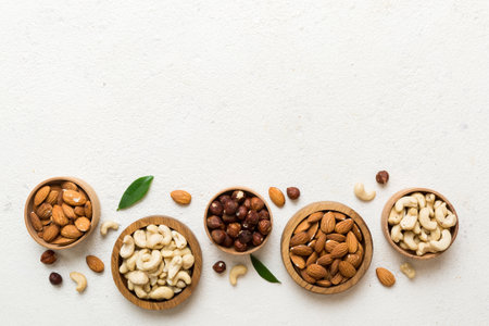 Assortment of nuts in wooden bowl on colored table. Cashew, hazelnuts, walnuts, almonds. Mix of nuts Top view with copy space.の写真素材