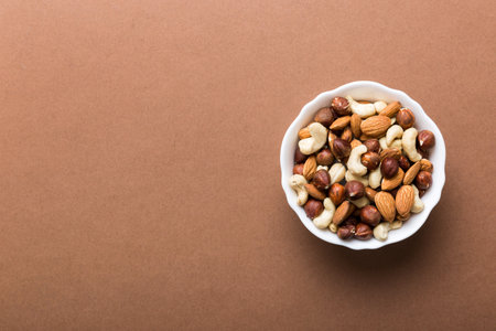 Assortment of nuts in wooden bowl on colored table. Cashew, hazelnuts, walnuts, almonds. Mix of nuts Top view with copy space.の写真素材