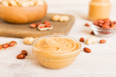 Bowl of peanut butter and peanuts on table background. top view with copyspace. Creamy peanut pasta...