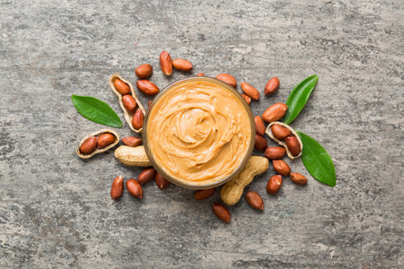 Bowl of peanut butter and peanuts on table background. top view with copyspace. Creamy peanut pasta...