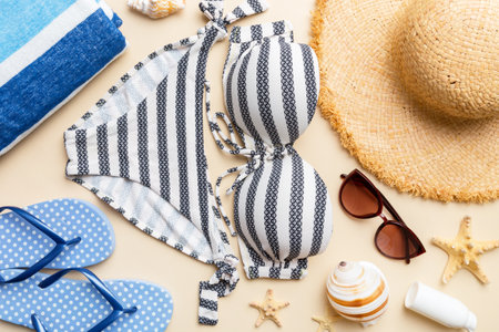 Woman swimwear and beach accessories flat lay top view on colored background Summer travel concept. bikini swimsuit, straw hat and seasheels. Copy space top view.の写真素材