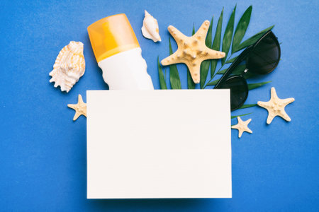 Summer time concept with blank greeting card and blank white paper on colored background. Seashells from ocean shore in the shape of frame separated with space for text top view.の写真素材