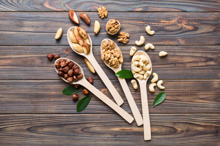 mixed nuts in white wooden spoon. Mix of various nuts on colored background. pistachios, cashews, walnuts, hazelnuts, peanuts and brazil nuts.の写真素材