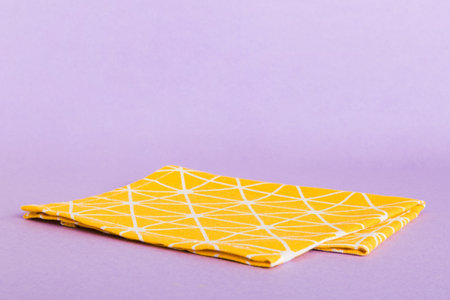 top view with yellow empty kitchen napkin isolated on table background. Folded cloth for mockup with...