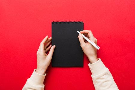 Woman hand with pencil writing on notebook. Woman working on office table. Female hand holding pencil and sketchbook. Mock-up concept.の写真素材