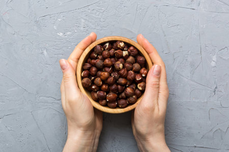 Woman hands holding a wooden bowl with hazelnut nuts. Healthy food and snack. Vegetarian snacks of various nuts.の写真素材