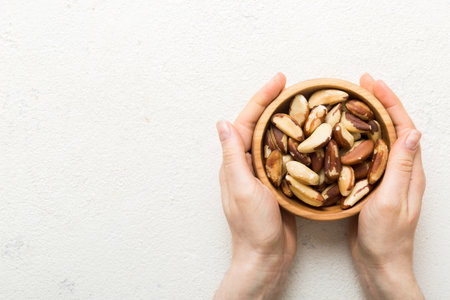 Woman hands holding a wooden bowl with brazil or bertholletia nuts. Healthy food and snack. Vegetarian snacks of various nuts.の写真素材