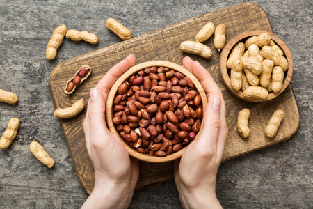 Woman hands holding a wooden bowl with peanuts. Healthy food and snack. Vegetarian snacks of various...