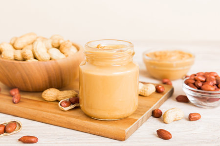 Bowl of peanut butter and peanuts on table background. top view with copyspace. Creamy peanut pasta...