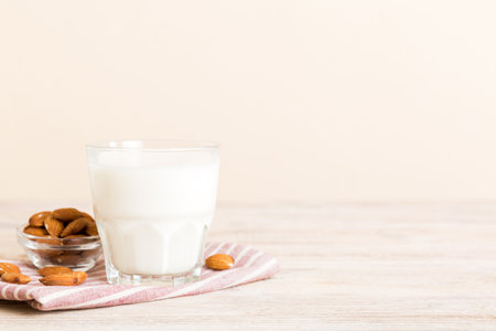 Top view of the almond milk in the glass bottle with almond nuts on the colored table. top view with copy space.の写真素材