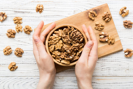Woman hands holding a wooden bowl with walnut nuts. Healthy food and snack. Vegetarian snacks of...